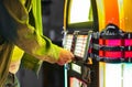 Male hand pushing buttons to play song on old Jukebox