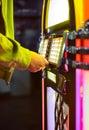 Male hand pushing buttons to play song on old Jukebox