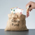 Male hand putting euro banknote in bag with crisis fund text. Royalty Free Stock Photo