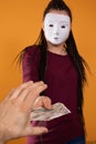 A male hand reaches for paper bills given by an anonymous young woman. An isolated figure on a solid orange color. Royalty Free Stock Photo