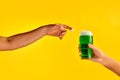 Male hand reaching glass with green foamy frothy beer over yellow background. Concept of st patrick& x27;s day Royalty Free Stock Photo