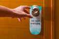 Male hand reaching to door knob with Do Not Disturb sign haning Royalty Free Stock Photo