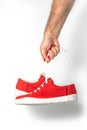 Male hand with red fingernails holding red sneakers Royalty Free Stock Photo