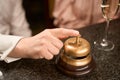 Male hand ringing golden service bell at counter desk in the bar