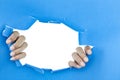 Male hand ripped blue paper on white background. Royalty Free Stock Photo