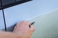 male hand scratches car wing with key