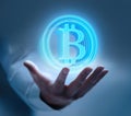 Male hand with a floating luminous Bitcoin symbol