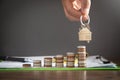 Male hand showing house keys over stack of coins Royalty Free Stock Photo