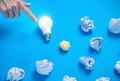 Male hand showing light bulb. Crumpled papers in the blue background. Idea Royalty Free Stock Photo