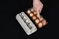 Male hand showing a plastic egg box instead of carton box full of hen eggs on black mat background Royalty Free Stock Photo