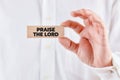 Male hand showing a wooden block with the message praise the lord