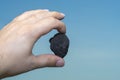 Male hand with a piece of coal on blue background Royalty Free Stock Photo