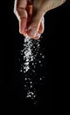 Male hand sprinkling edible salt at black background Royalty Free Stock Photo
