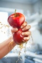 A male hand squeezes fresh juice. Pure apple juice pouring out from fruit into glass Royalty Free Stock Photo