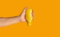 Male hand squeezing bottle with mustard on orange background, closeup. Space for text Royalty Free Stock Photo