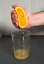 Male hand squeezing an orange into a glass Royalty Free Stock Photo