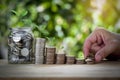 Male hand stack coins and layer to show keep money step and money in a jar with tree on top. Royalty Free Stock Photo