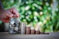 Male hand stack coins and put money in a jar with tree on top and a jar to show growing concept business,wealthy,education,house Royalty Free Stock Photo