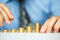 Male hand stacking gold coins into increasing columns