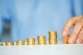 Male hand stacking gold coins into increasing columns