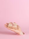 A male hand sticks out of a hole in paper on a pink background, holds a craft gift. Christmas concept, print blank, copy space