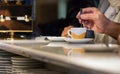 A male hand stirring an espresso coffee cup sitting in a bar counter in Italy, indoors