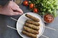 Male hand taking a delicious piece of lule kebab for testing satsebeli sauce,top view