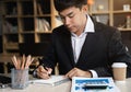 Male hand taking notes on a notebook handwritten note writing business schedule and use a laptop computer at the office desk Royalty Free Stock Photo