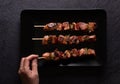 Male hand taking a skewer of freshly made pieces of chicken with red and green peppers