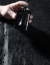 Male hand from total dark holding bottle of fragrance.Vertical shot of expensive perfume Royalty Free Stock Photo