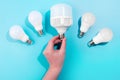 male hand touch big LED light bulbs on blue color background with little led lamps. Flat lay with copy space Royalty Free Stock Photo