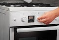 Male hand turning on white kitchen gas stove on gray Royalty Free Stock Photo