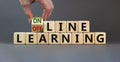 Male hand turns the cube and changes the expression `offline learning` to `online learning`. Beautiful grey background. Busine