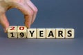 Male hand turns cubes and changes the expression `19 years` to `20 years` or vice versa. Beautiful grey background. Business a