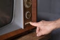 male Hand turns on TV power button, adjusts volume control old retro analog TV, entertainment, Technologies of Past Decades Royalty Free Stock Photo