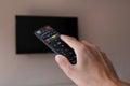 Male hand with tv remote control and blurred television with a black screen Royalty Free Stock Photo