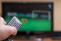 Male hand with a TV remote control close-up. Football fan watching match. Soft focus Royalty Free Stock Photo