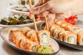 Male hand with two chopsticks holding Uramaki Philadelphia sushi roll Royalty Free Stock Photo