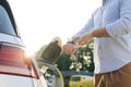 Male hand unplugs power connector into EV car and charges batteries, uses smart watch to disconnect charging. Man