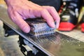 Male hand using a Brass brush to clean the structure of a ski base. Ski tuning and maintenance tool.