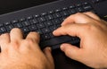 Male hand using pc keyboard. Close up man hand on computer keyboard on black wooden background Royalty Free Stock Photo