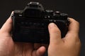 Male hand using photo camera. Close up man hand on photo camera on black wooden background Royalty Free Stock Photo