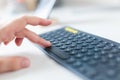 Male hand using wireless computer keyboard on table at office. Blurry smartphone and dock on the background