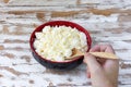 Male hand with a wooden spoon mixing yellow fresh homemade cottage cheese