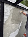 Male hand working with cement on brick wall, creating decorative texture. Concept of construction, renovation Royalty Free Stock Photo