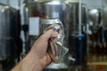 Male hand wrinkles an empty aluminum can on the background of beer equipment