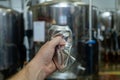 Male hand wrinkles an empty aluminum can on the background of beer equipment