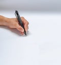 Male hand writes a black pen on white paper Royalty Free Stock Photo