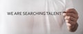 Male hand writes We Are Searching Talent text