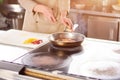 Male hands adding pepper to frying pan.